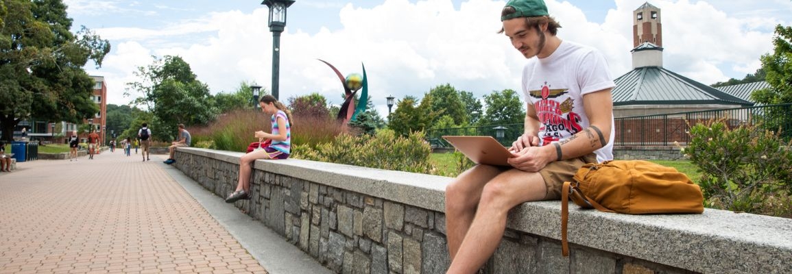 A student looks at their laptop on Sanford Mall at Appalachian State University.
